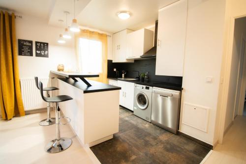 a kitchen with white cabinets and a washer and dryer at Le Joyau T2-55m2 Centre ville 10min Disney in Bussy-Saint-Georges