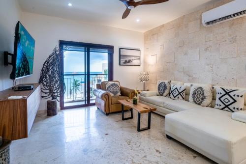sala de estar con sofá y TV en Condo Surf 405 - Luxury Oceanview Beachfront 3 BR with Gym - At El Faro Condos, en Playa del Carmen