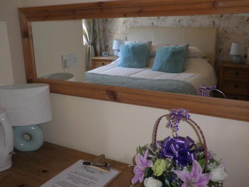 a bedroom with a bed with a large mirror at Longfrie Inn in St Saviour Guernsey