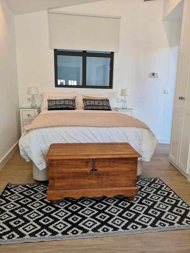 a bedroom with a large bed with a wooden table at Casa Rural Albireo, rebosante de luz y naturaleza in Sanlúcar de Guadiana