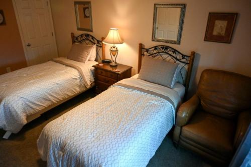a bedroom with two beds and a chair and a lamp at The Adamina in Fairbanks