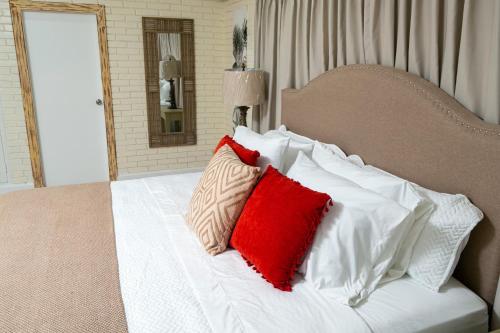 a bedroom with a bed with red and white pillows at Angeli Gardens Boutique Hotel in San Pedro Sula