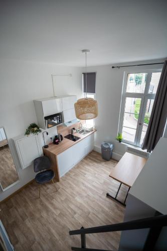 une cuisine avec des armoires blanches et un plancher en bois dans l'établissement Residence des Wetz Studios équipés - Centre-idéal Parc Expos, à Douai