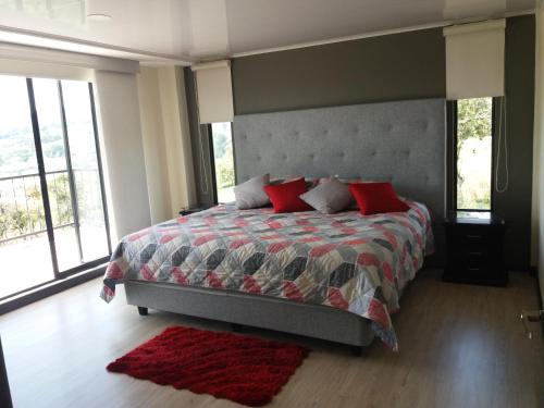 1 dormitorio con 1 cama grande con almohadas rojas en Sierra Morena, en Cogua
