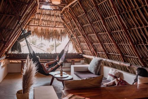 a woman laying in a hammock in a thatched room at Swell in El Paredón Buena Vista