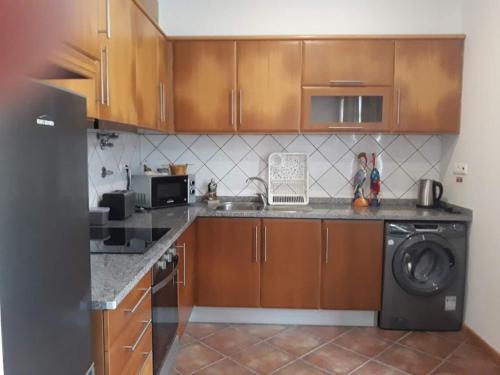 a kitchen with wooden cabinets and a washer at House Bali Furnas in Furnas