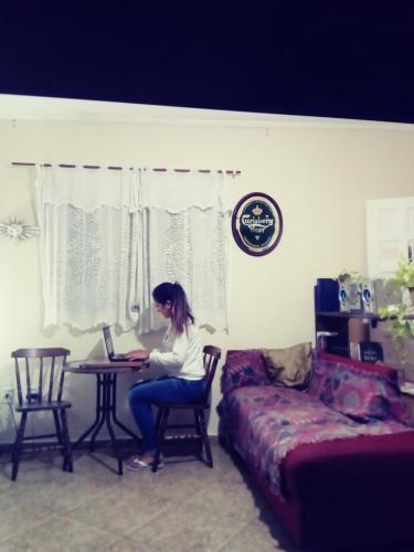 a woman sitting at a table with a laptop at Mayda hostel in Praia Grande