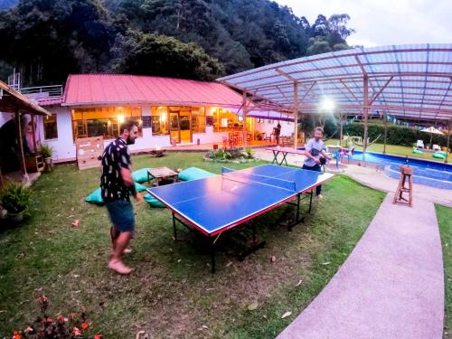 a man standing next to a ping pong table at Mama Tungu hostel in Baños
