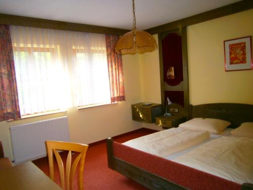 1 Schlafzimmer mit 2 Betten, einem Tisch und 2 Fenstern in der Unterkunft Gasthof Drei Linden in Obertrubach