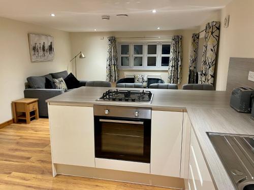 a kitchen with a stove top oven next to a living room at The Annex at Pantglas Farm in Pontyclun