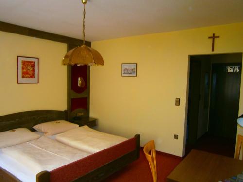 a bedroom with a bed and a cross on the wall at Pension Drei Linden in Obertrubach