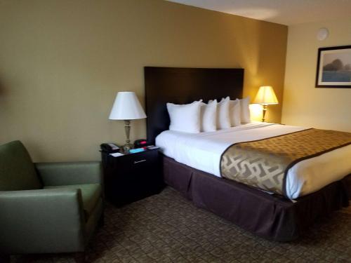 デフニアック・スプリングスにあるBest Western Crossroads Innの大きなベッドと椅子が備わるホテルルームです。