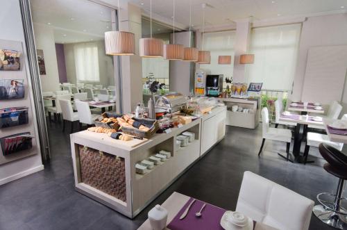 a restaurant with a counter with food on it at Best Western Plus Hotel Plaisance in Villefranche-sur-Saône