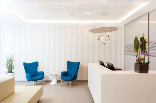 a lobby with blue chairs and a reception desk at NH Collection Wien Zentrum in Vienna