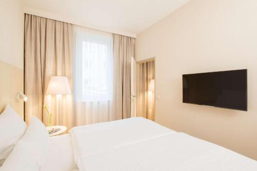 
a hotel room with two beds and a television at NH Collection Wien Zentrum in Vienna

