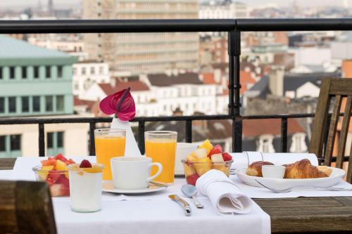 a table with breakfast foods and drinks on a balcony at NH Collection Brussels Centre in Brussels