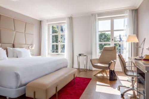 a bedroom with a large white bed and a desk at NH Collection Brussels Grand Sablon in Brussels