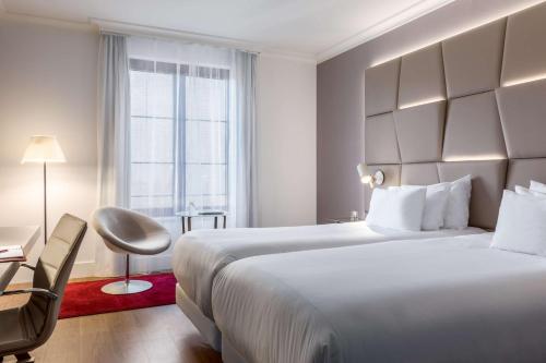 a hotel room with a large white bed and a window at NH Collection Brussels Grand Sablon in Brussels