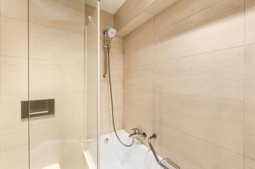 una doccia con porta in vetro in bagno di NH Hotel Stephanie a Bruxelles