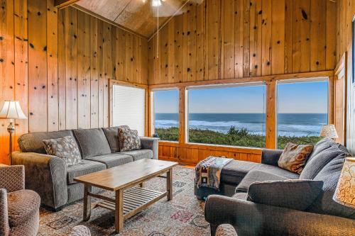 a living room with couches and a table and windows at Coastal Serenity in Lincoln City