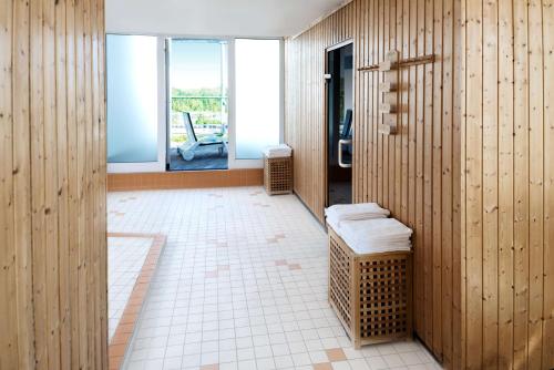 ライプツィヒにあるNH ライプツィヒ メッセの白いタイルフロアのバスルーム(木製の壁付)