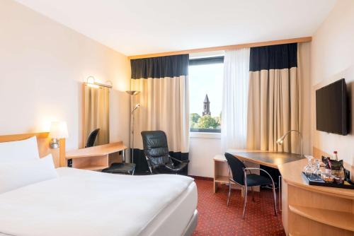 a hotel room with a bed and a desk and a bed and a room with at NH Oberhausen in Oberhausen