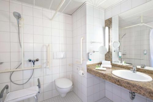 a bathroom with a sink and a toilet and a shower at NH Oberhausen in Oberhausen