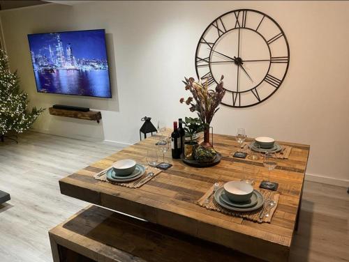 a dining room table with a large clock on the wall at EXCLUSIVE and MODERN - Bradford City Centre- 85" Cinema TV in Bradford