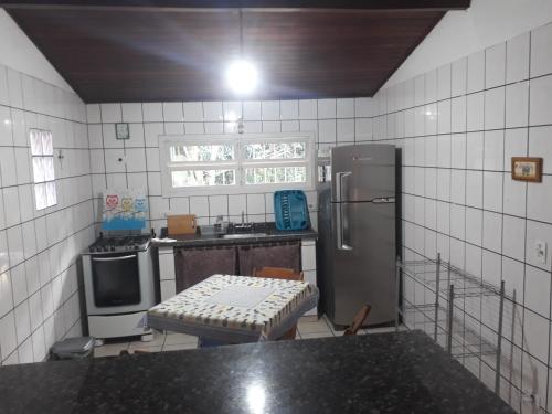 cocina con nevera y mesa. en Aconchego 3 dorms, piscina, churrasq em Condomínio Fechado, en Boicucanga
