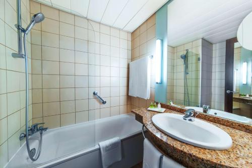 a bathroom with a sink and a tub and a shower at NH Budapest City in Budapest