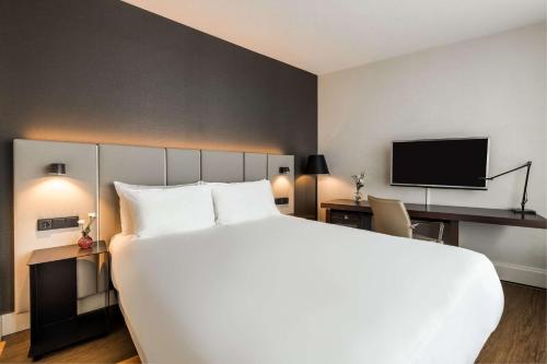アムステルダムにあるNH アムステルダム カランサの大型ベッドとテレビが備わるホテルルームです。
