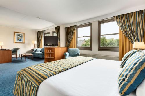een hotelkamer met een groot bed en een televisie bij NH Bussum Jan Tabak in Bussum