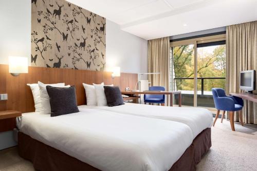 ヌンスペートにあるFletcher Hotel-Restaurant Sparrenhorst-Veluweの大きなベッドとデスクが備わるホテルルームです。