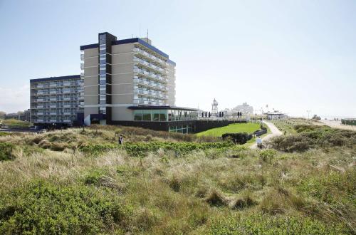 a building on top of a hill next to the beach at NH Atlantic Den Haag in The Hague