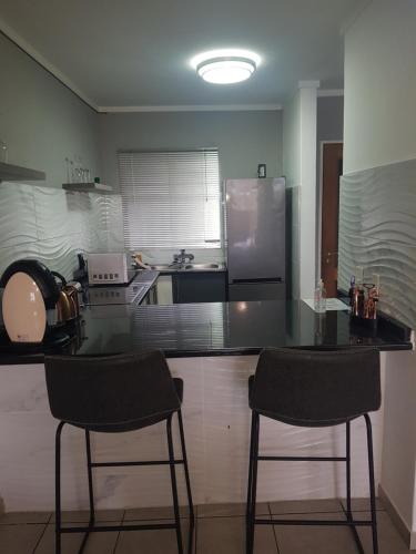 a kitchen with two bar stools and a refrigerator at Menlyn Place in Pretoria