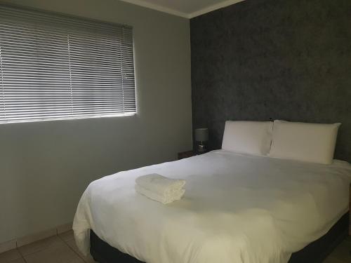 a bedroom with a large white bed with a window at Menlyn Place in Pretoria