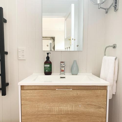 a bathroom sink with a bottle of alcohol on it at Ohariu Farm Cottage in Johnsonville