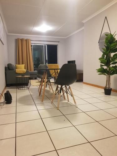 a living room with a table and chairs on a tiled floor at Menlyn Place in Pretoria