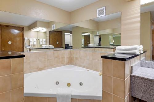 een grote badkamer met een bad en een grote spiegel bij SureStay Hotel by Best Western Lenoir City in Lenoir City