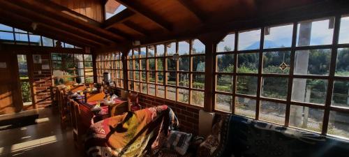 a large room with windows with a view of the forest at Cuscungo Cotopaxi Hostel & Lodge in Chasqui