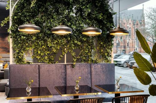 a dining room with a green wall with plants at NH Hannover in Hannover