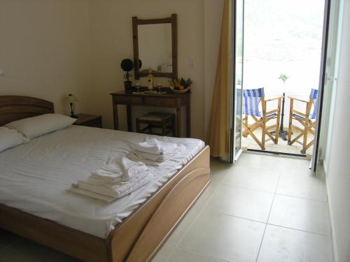 a bedroom with a bed with white sheets and a balcony at Psaropoula in Balíon