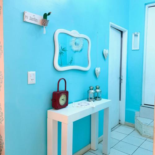 Zimmer mit einer blauen Wand, einem Tisch und einer Uhr in der Unterkunft Tuchita House en Cataratas con piscina compartida parrilla, cochera in Puerto Iguazú