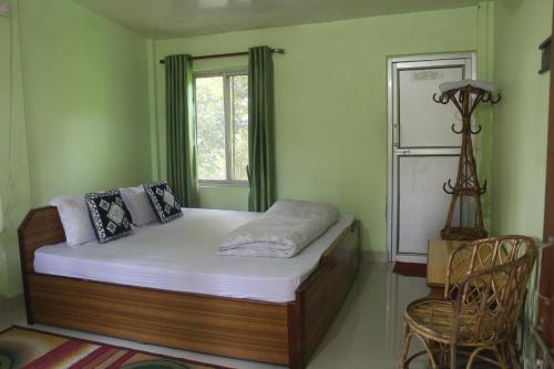 Schlafzimmer mit einem Bett, einem Fenster und einem Stuhl in der Unterkunft Shuklaphanta Jungle Cottage in Bahāsi