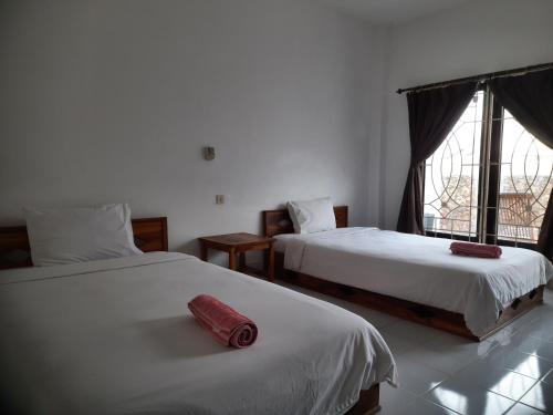 a bedroom with two beds and a red object on the bed at Spear Villa in Bumbang