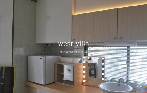 a kitchen with a counter with a refrigerator and a sink at West Villa in Naha