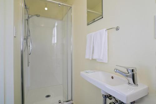 y baño blanco con lavabo y ducha. en Glendhu Station Cottage - Glendhu Bay Holiday Home en Glendhu