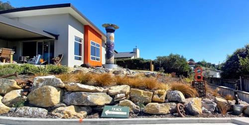 a house with a pile of rocks in front of a yard at Grampians B&B in Nelson