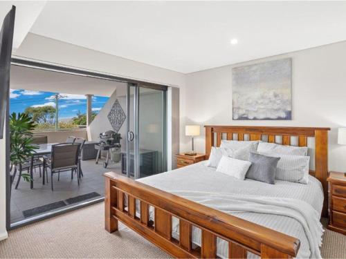 a bedroom with a bed and a balcony with a table at Villa Serene 3 in Fingal Bay