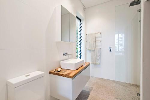 a white bathroom with a sink and a toilet at BRON455B - Bronte Beach House with Ocean Views in Sydney